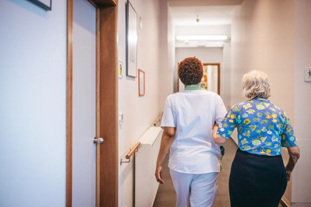 Une soignante accompagne une personne âgée dans les couloir de la résidence