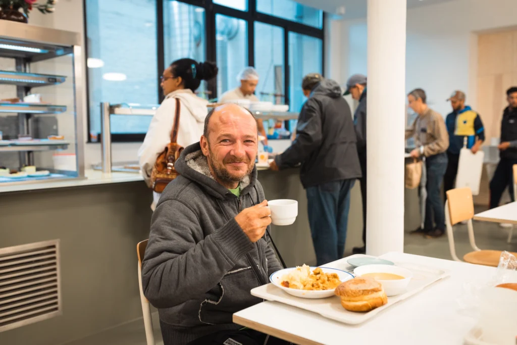 Une personne souriante entrain de boire son café et manger son repas